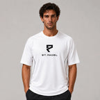 St. Padel Performance Padel T-Shirt. A man wearing a white short-sleeve athletic t-shirt with a black St. Padel logo on the chest, standing against a neutral gray studio background.