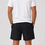 St Padel Performance Shorts. A man wearing black athletic shorts and a white t-shirt, shown from the back against a light gray studio background.