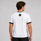 St. Padel V-Neck Jersey. A man viewed from the back wearing a white short-sleeve athletic jersey with black trim at the collar and sleeve cuffs, plus black side stripes and a circular black logo near the upper back.