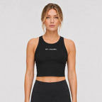 St. Padel Women's Crewneck Crop Tank Top. A woman modeling a black athletic crop top with 'ST. PADEL' printed in white on the chest, paired with black athletic bottoms, against a light gray studio background.